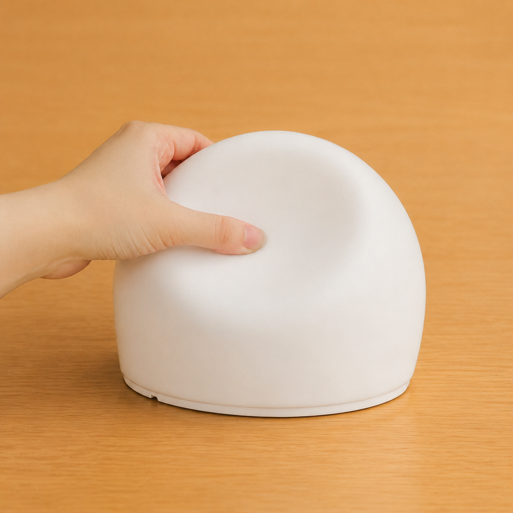 A hand gently pressing the soft silicone dome of the sensory bubble light.