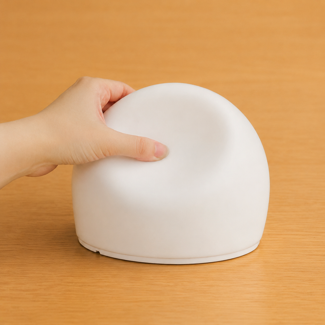 A hand gently pressing the soft silicone dome of the sensory bubble light.